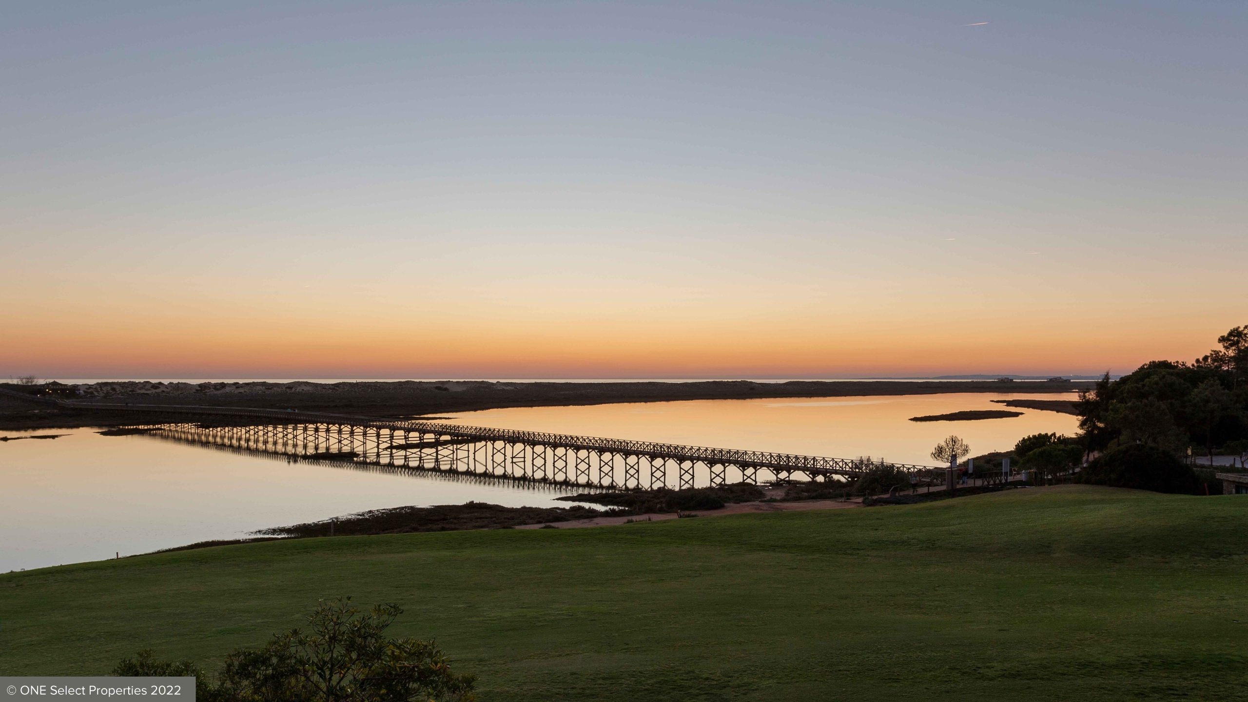 beautiful sunset with ancão bridge ria formosa lake and dunes in background