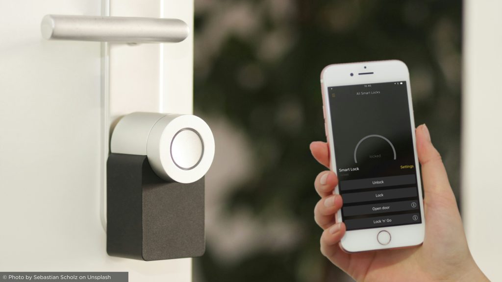 Fechadura inteligente sendo controlada por um aplicativo móvel para entrada segura e sem chave em uma casa moderna, aumentando a conveniência e a segurança